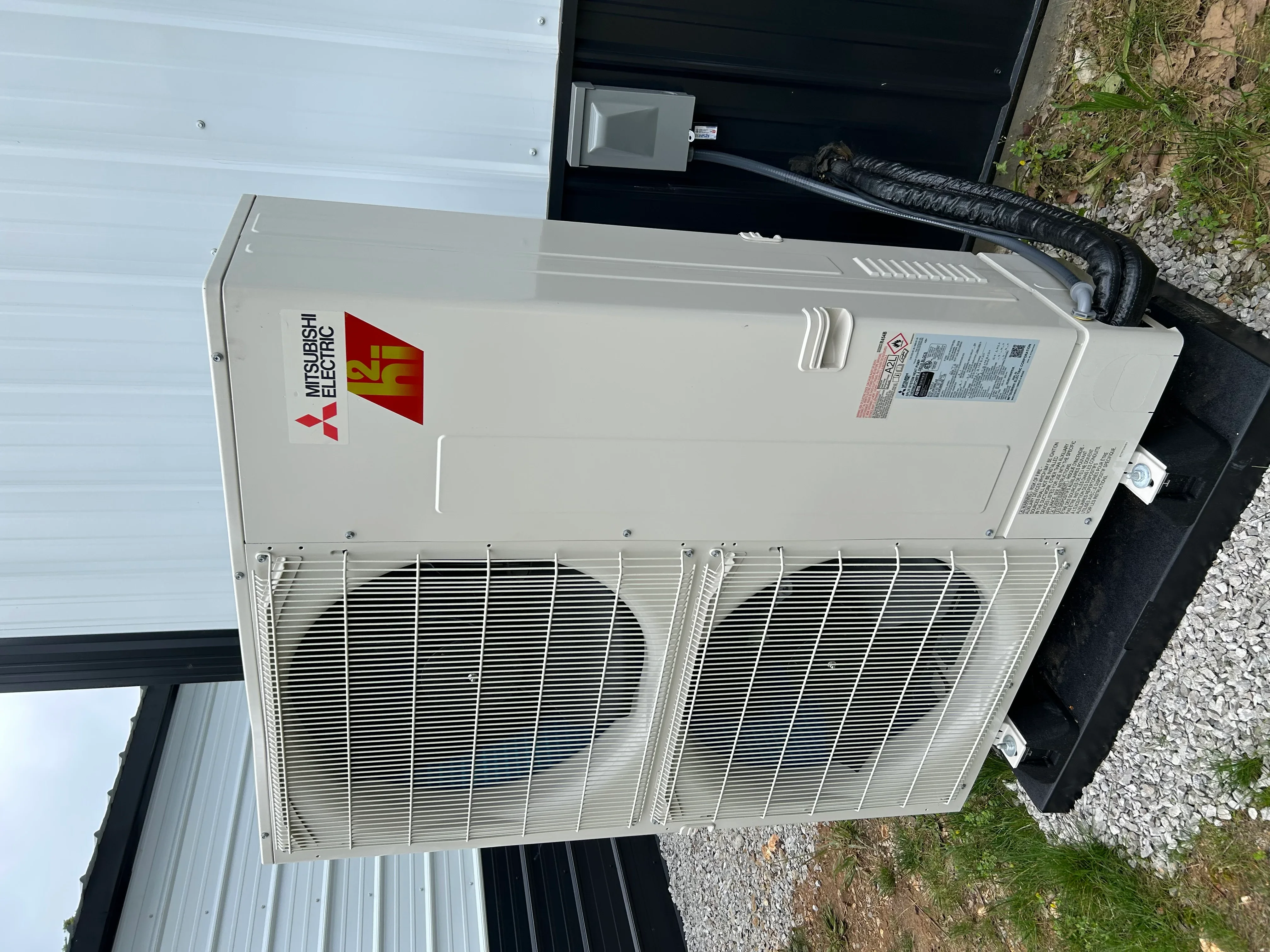 Mitsubishi Electric heat pump outdoor unit with dual fans and refrigerant lines installed