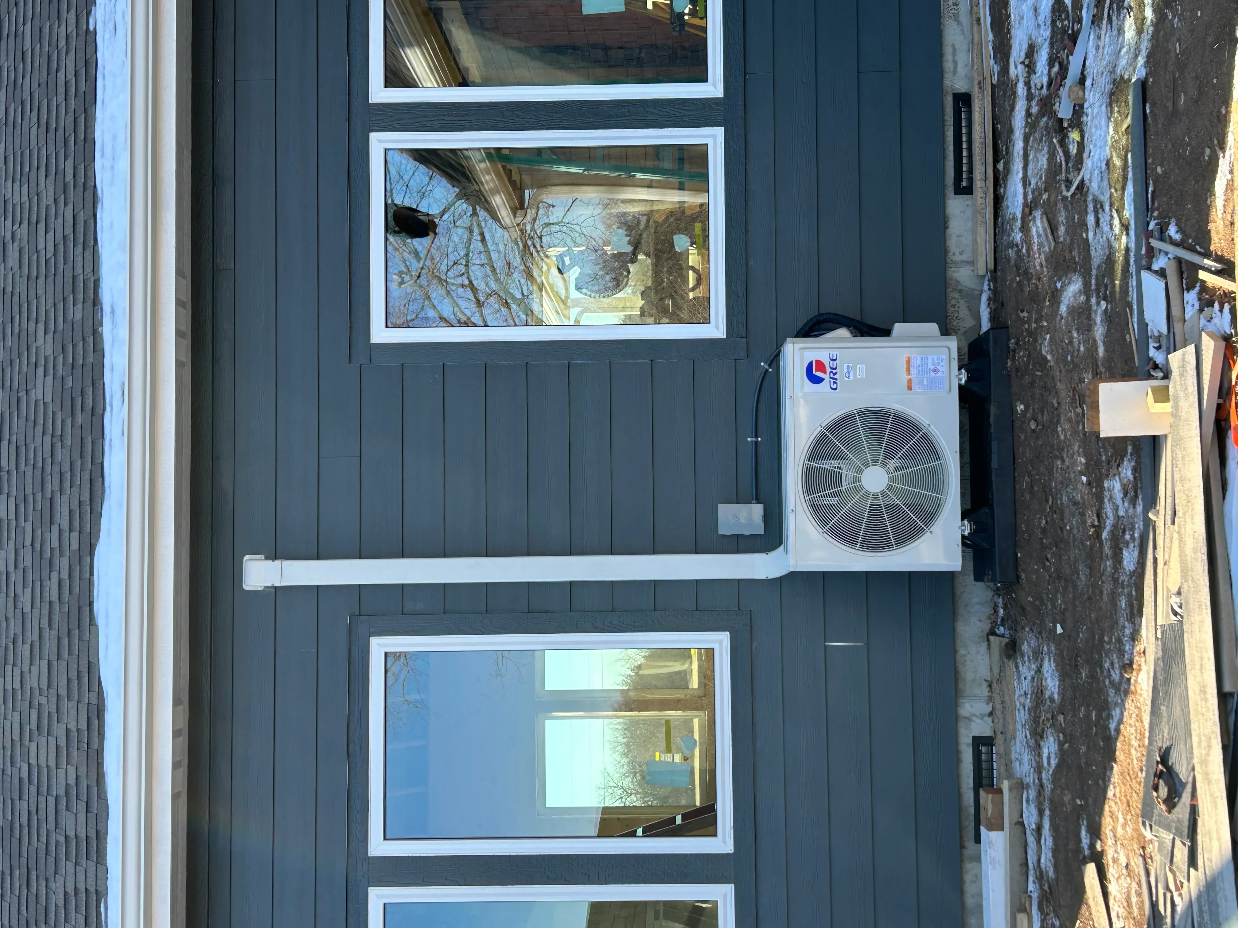 Gree ductless mini-split outdoor condenser and indoor wall-mounted air handlers on corrugated metal siding